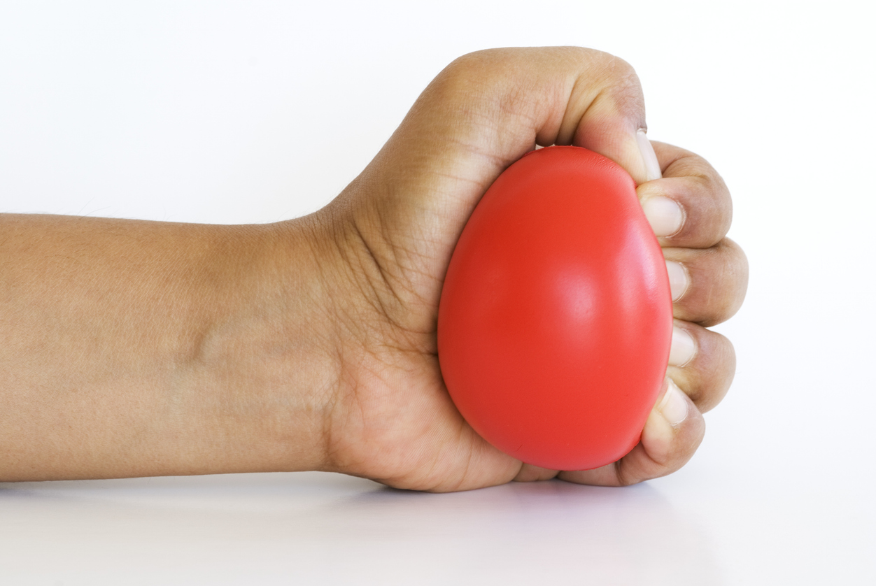 Hand squeezing stress ball isolated on white background with copy space